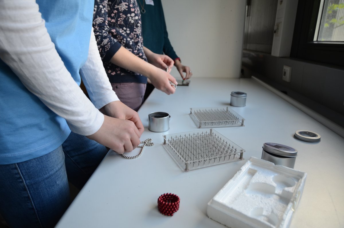 Schülerinnen experimentieren mit Mangetnadelnmodeln und Magnetkugeln