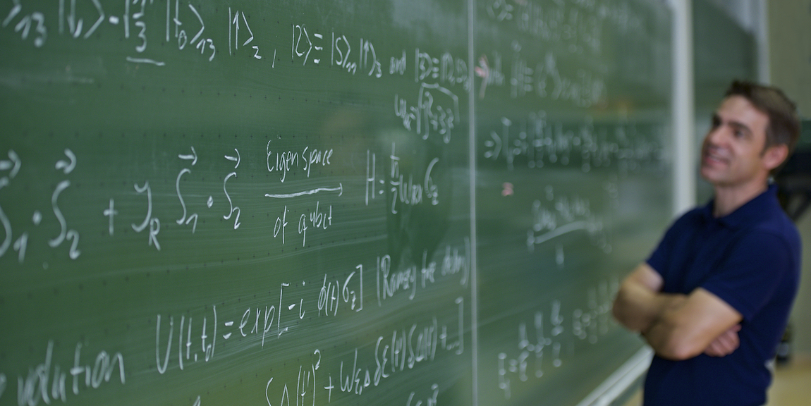 Professor in front of a blackboard with formulas